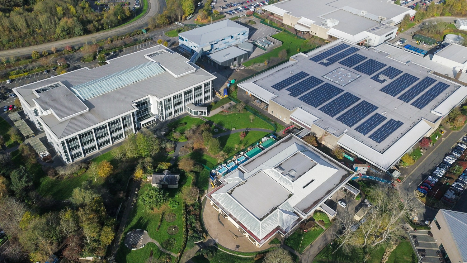 Aerial view of commercial buildings with rooftop solar panels, showing installation suitable for solar panel load calculator estimates.