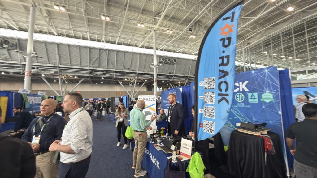 Top Rack Technology booth at RE+ Northeast Boston 2026 featuring rooftop solar racking displays and team members engaging with installers and industry professionals.